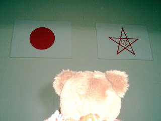 体育館中央のステージには,日本の国旗と学校のシンボルマークが掲げてあります。